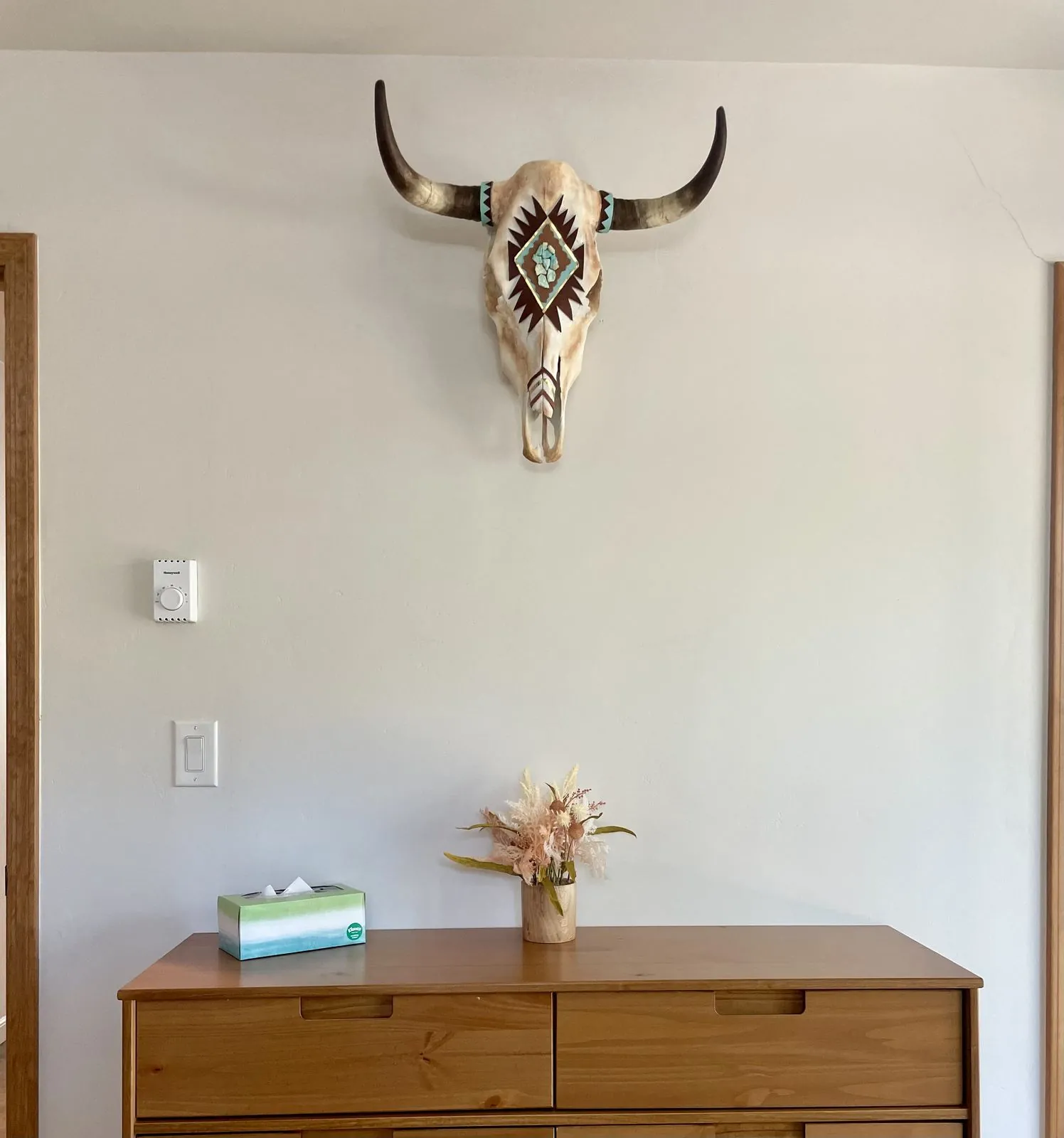Painted cow skull decor above the primary bedroom dresser