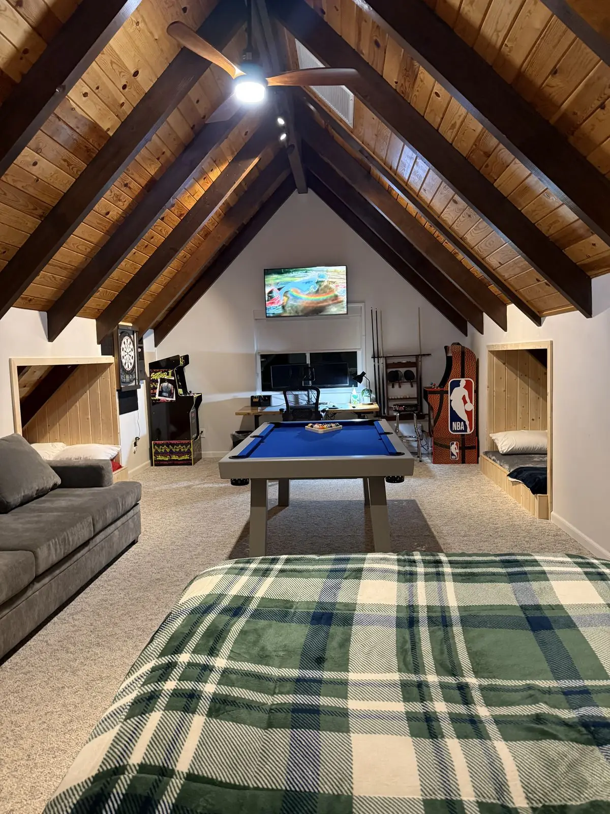 Pool table with TV and arcade cabinets in the loft game room
